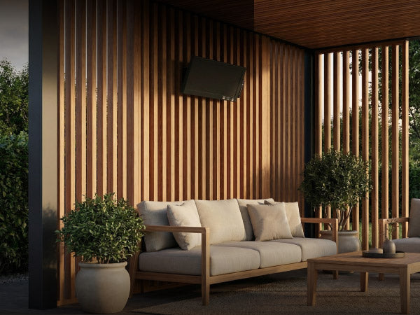 Elegante schwarze Bringer Infrarotheizung, montiert an einer modernen Holzwand-Verkleidung auf einer überdachten Terrasse mit gemütlichen Lounge-Möbeln